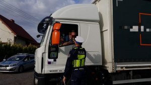 Policjant ruchu drogowego sprawdza stan trzeźwości kierującego samochodem ciężarowym