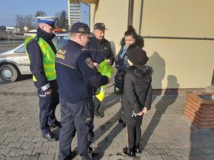 Policjanci wspólnie ze Strażą Gminną przekazują kamizelkę odblaskową pieszym