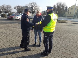 Policjanci wspólnie ze Strażą przekazują kobiecie kamizelkę odblaskową