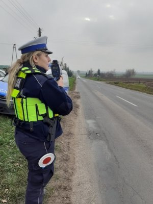 Policjantka na drodze mierzy prędkość pojazdów